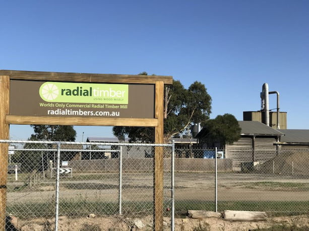 Radial timber sign in foreground, Timber mill in background  